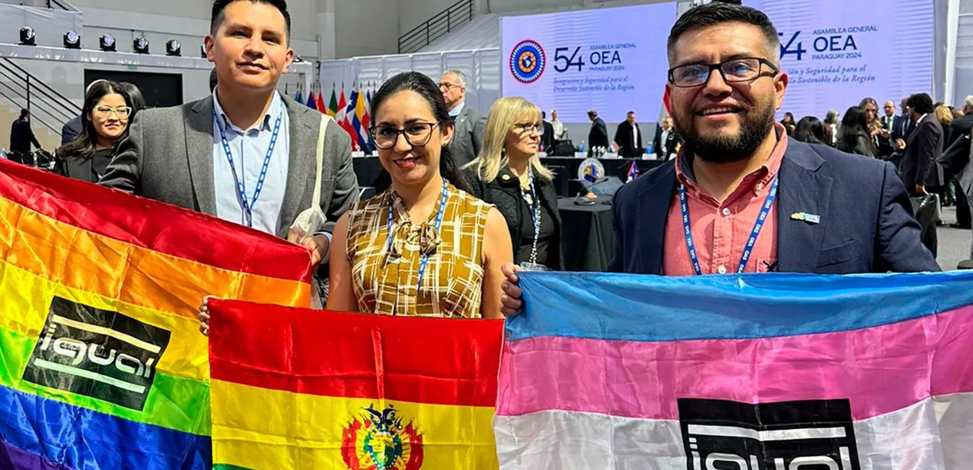 Mateo (rechts, met de transgendervlag) en activisten van IGUAL met de regenboog- en Boliviaanse vlag bij de Algemene Vergadering van de OAS.